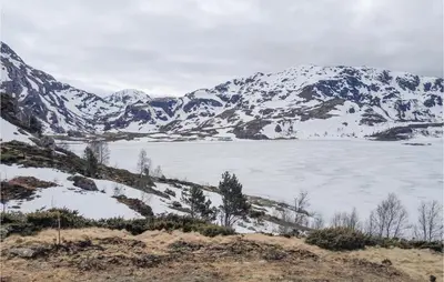 a snow covered mountain with a lake in the foreground at 4 Bedroom Nice Home In Etne in Etnesjøen