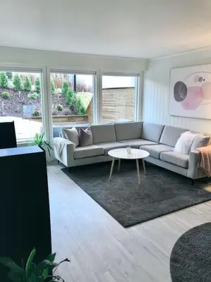 a living room with a couch and a table at Moderne og sentral leilighet med koselig og privat uteplass! in Hornnes