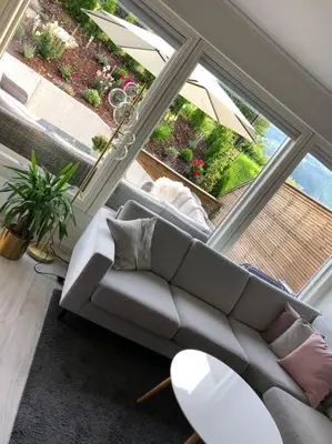a living room with a couch and a large window at Moderne og sentral leilighet med koselig og privat uteplass! in Hornnes