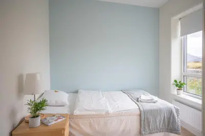 a white bedroom with a bed and a window at Runde Miljøsenter & Opplev Runde in Runde