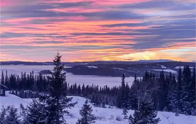 a sunset in the mountains with snow and trees at Stunning Home In Øyer With Sauna in Øyer