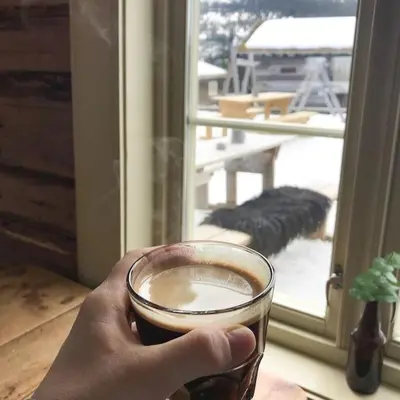 a person holding a cup of coffee in front of a window at Cozy apartment in Hafjell - Øyer centre in Hafjell