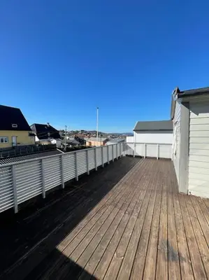 a wooden deck with a white fence and a building at Lovely 2 bedroom apartmen with free parking in Bergen