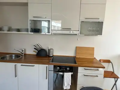 a kitchen with white cabinets and a wooden counter top at Marken Studio Apartments in Bergen