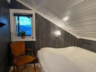 a bedroom with a bed and a chair and a window at Stor hytte med 4 soverom og panoramautsikt over Tinnsjøen ved Rjukan og Gaustatoppen in Håkånes