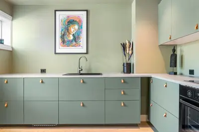 a kitchen with blue cabinets and a painting on the wall at Trolltunga View in Tysso