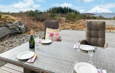 a table with plates and a bottle of wine and chairs at Gorgeous Home In Sveio With Wifi in Sveio