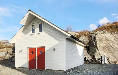 a small white building with red doors next to a rock at Gorgeous Home In Sveio With Wifi in Sveio