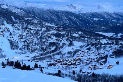 a village in the snow with mountains in the background at Roalden Mountain Lodge in Stranda
