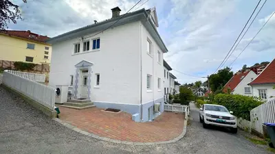 a white house with a car parked in front of it at Ibsens apartaments in Bergen