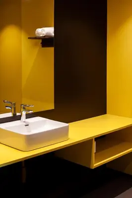 a yellow bathroom with a sink and a mirror at Elva Hotel in Vossevangen