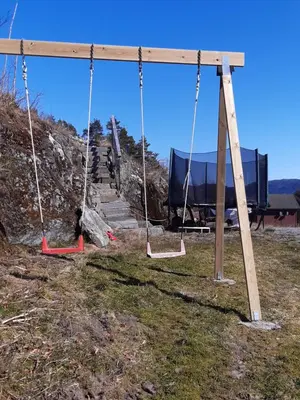 a swing set in a field with a building in the background at Leilighet Vikaparken Hardangerfjord in Hatlestrand