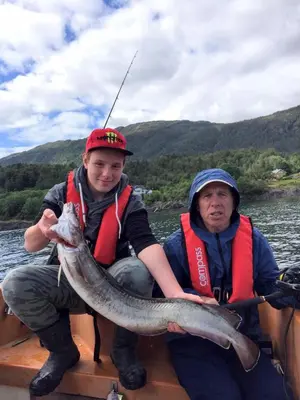 a man and a boy on a boat with a large fish at Leilighet Vikaparken Hardangerfjord in Hatlestrand