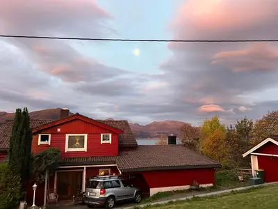 a car parked in front of a red house at Line på Hauane1 in Volda