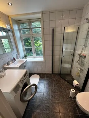 a bathroom with a shower sink and a washing machine at Modern Apartment in the center of Bergen in Bergen
