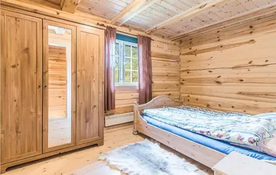 a log cabin bedroom with a bed and a window at Beautiful Home In Dalholen With Sauna in Furuhovde