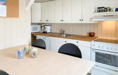 a kitchen with white cabinets and a table with a candle at Stunning Home In Ålesund With Kitchen in Ålesund