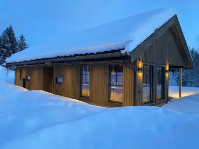 a house covered in snow with a pile of snow at Stryn Mountain Lodge in Stryn