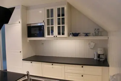 a kitchen with white cabinets and a microwave at Rosendal Hyttetun in Rosendal