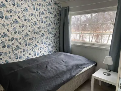 a bedroom with a bed and a window with blue flowers at Rosendal Apartments Motellet in Rosendal