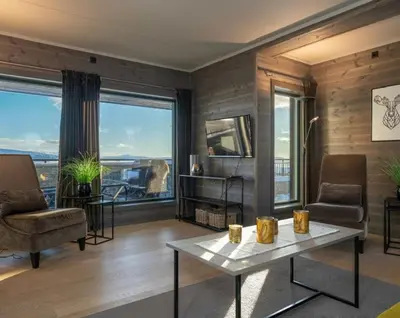 a living room with a table and chairs and windows at Riddertunet apartment 104 - in the center of Beitostølen in Beitostøl