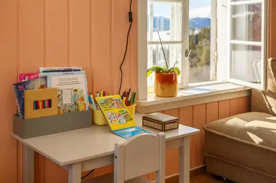 a table with books and a chair next to a window at Vinjestogo- mesmerizing mountain view, sauna with a view and eco living in an old school house in Løken