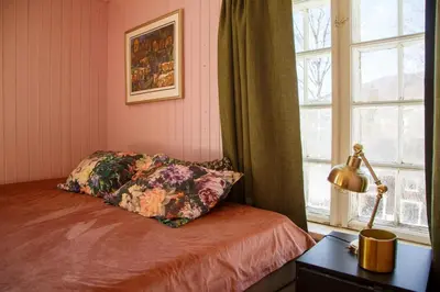 a bedroom with a bed with a pillow and a window at Vinjestogo- mesmerizing mountain view, sauna with a view and eco living in an old school house in Løken