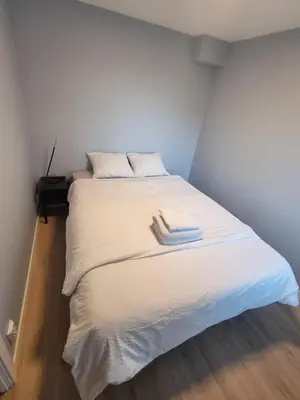 a bed with white sheets and two towels on it at Near Bergen City, Apartment 7 min from the airport, free parking in Bergen