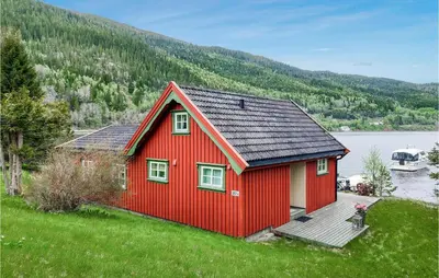 a red house on the side of a lake at Cozy Home In Mosvik With House Sea View in Mosvik