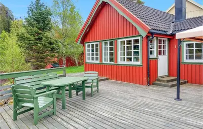 a red house with a picnic table and benches on a deck at Cozy Home In Mosvik With House Sea View in Mosvik