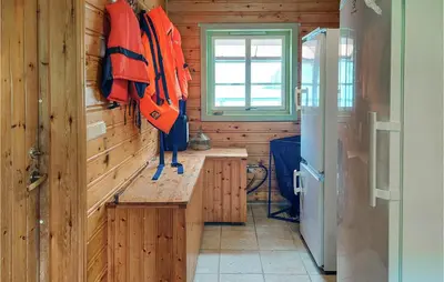 a kitchen with wooden walls and a window and a refrigerator at Cozy Home In Mosvik With House Sea View in Mosvik