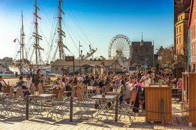 a crowd of people sitting at tables at a harbor at Dinbnb Apartments I Mid-City Luxury with Mini Balcony and Smart TV & Sound System in Bergen