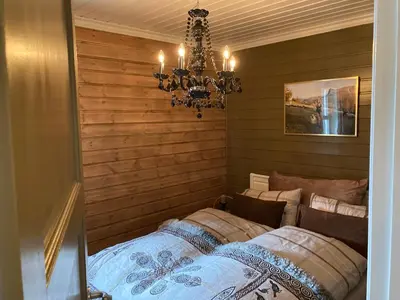 a bedroom with a bed and a chandelier at Lun og koselig hytte med sauna på Filefjell in Tyinkrysset