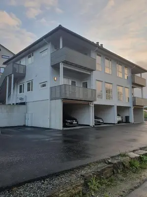 a large white building with a parking lot at Nydelig leilighet- Solrik/2 balkonger in Seim