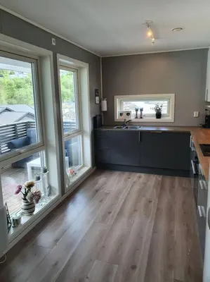 a large kitchen with wooden floors and large windows at Nydelig leilighet- Solrik/2 balkonger in Seim