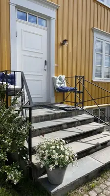 a porch with stairs with a door and a chair at Tomannsbolig på Rosenborg in Trondheim