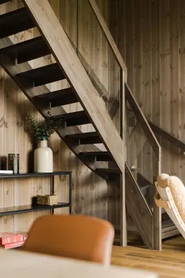 a wooden staircase in a living room with a chair at Luxury Nordic Suite with Private Sauna and Panoramic Mountain Views in Stranda