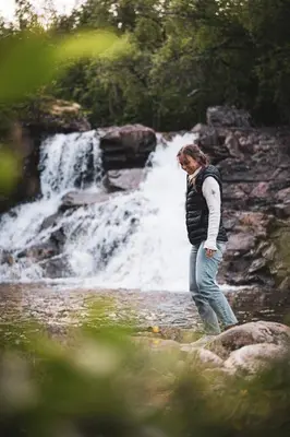 a woman standing in front of a waterfall at Luxury Nordic Suite with Private Sauna and Panoramic Mountain Views in Stranda