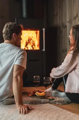 a man and a woman sitting on the floor with wine glasses at Luxury Nordic Suite with Private Sauna and Panoramic Mountain Views in Stranda