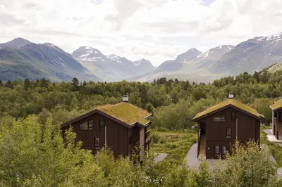 a group of buildings with mountains in the background at Luxury Nordic Suite with Private Sauna and Panoramic Mountain Views in Stranda