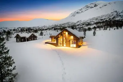 a cabin in the snow with the lights on at Tonningssætra Mountain Lodge in Stryn