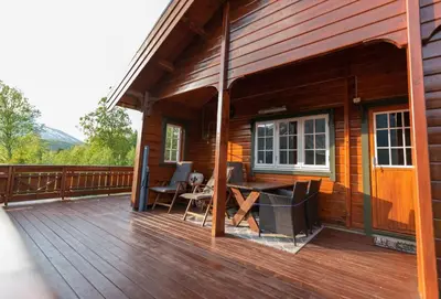 a porch of a wooden cabin with a table and chairs at Cabin near the lake in Årset