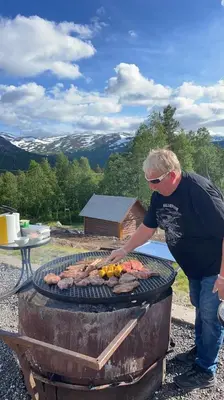 a man is cooking meat on a grill at Kårdal Fjellstove in Mjølfjell