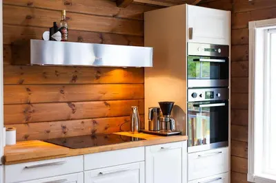 a kitchen with white cabinets and a wooden wall at Luxury cabin in the mountains with all facileties in Sønstebø