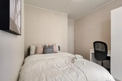 a bedroom with a bed and a black chair at Family Friendly - Modern - City Central in Bergen