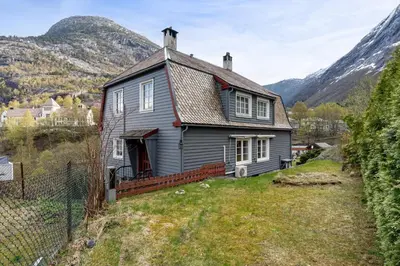 an old gray house with mountains in the background at Tysso Apartment in Tveit
