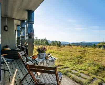 a table and chairs on a porch with a view of a field at Leilighet sentralt på Beitostølen in Beitostøl