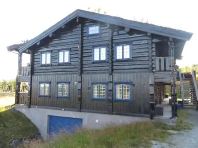 a large wooden house with a blue door at Leilighet sentralt på Beitostølen in Beitostøl