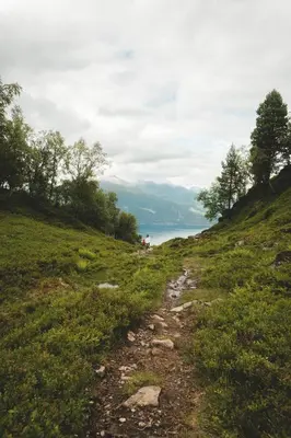 a trail on a hill with a lake in the background at Luxurious 5-Bedroom Mountain Chalet with Sauna, Panoramic Views, and Two Full Bathrooms in Stranda