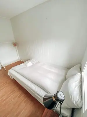 a small bedroom with a bed with white sheets at Trolltunga Sleep in Tveit